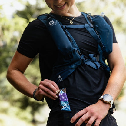 sports woman putting Moonvalley Organic Energy Bars Oats & Dates Chocolate & Sea Salt in the pocket